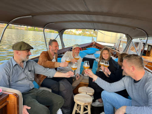 A group clinks glasses during a boat trip with beer tasting on the Neckar