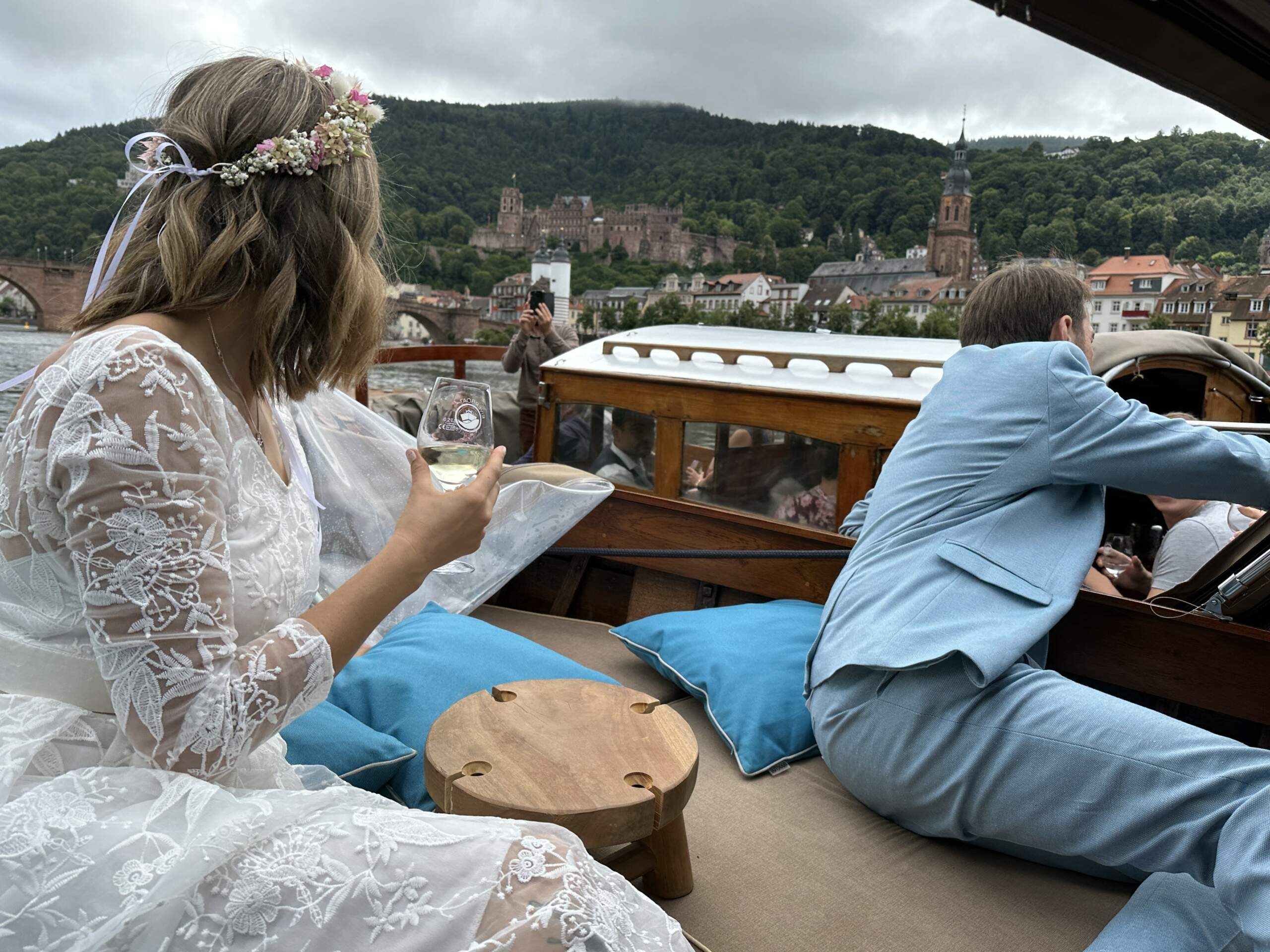 Ein Hochzeitspaar feiert an Bord eines Bootes von Riverboat Hochzeit, daneben fahren ihre Hochzeitsgäste in einem zweiten Holzboot direkt daneben