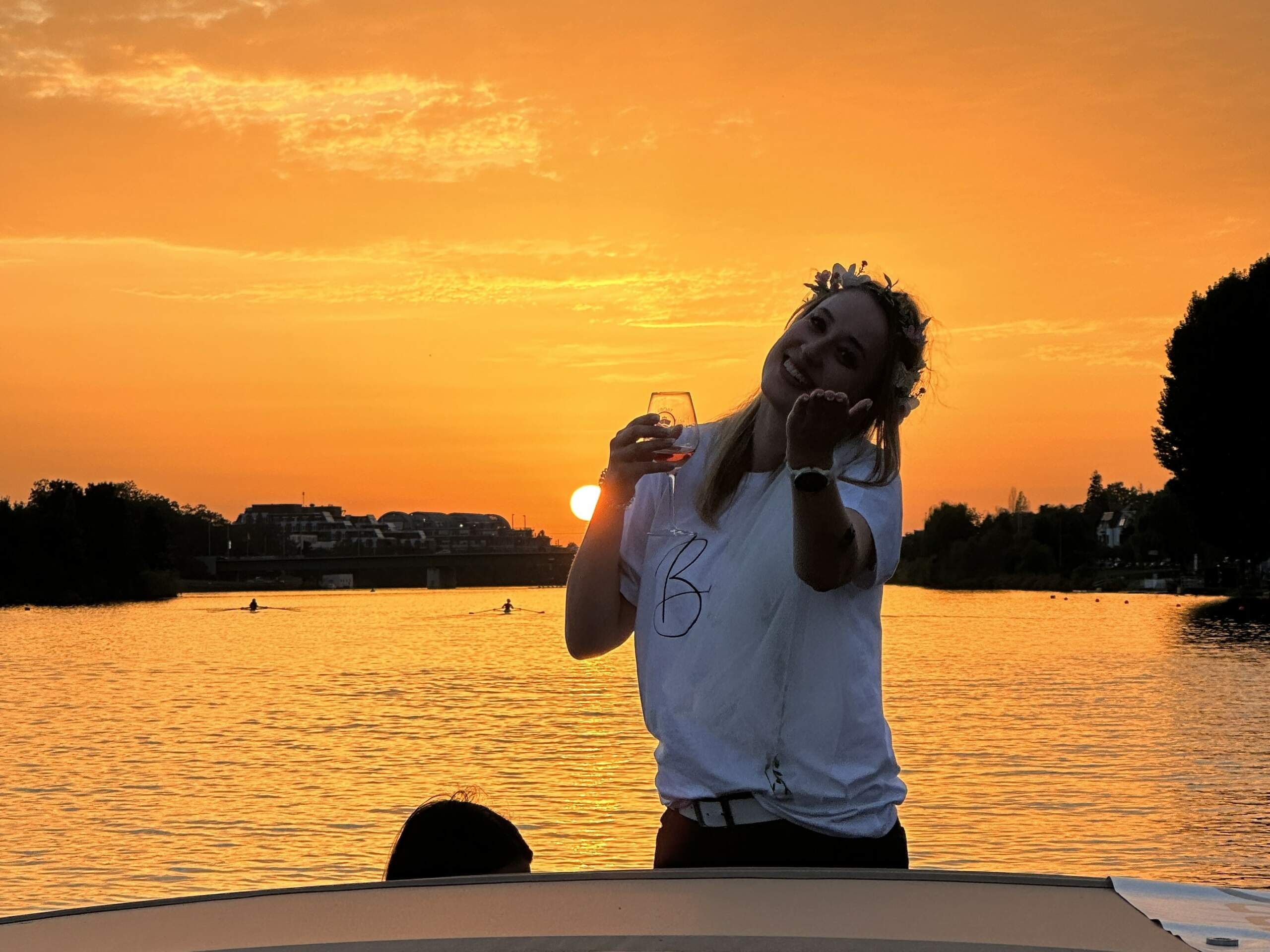 Eine Junggesellin feiert JGA an Bord des Riverboats mit einem Glas Wein in der Hand vor dem Sonnenuntergang am Neckar