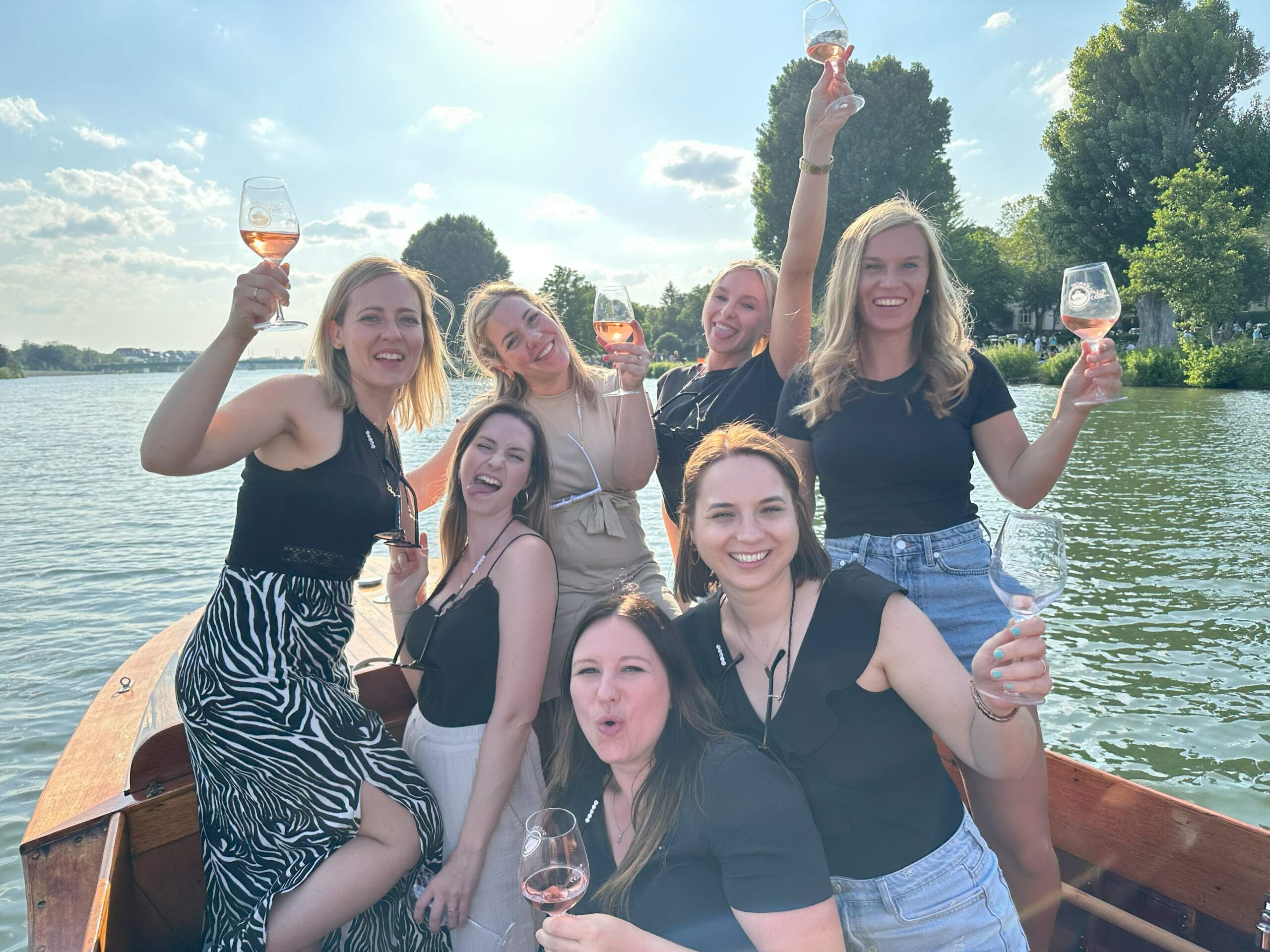 Eine Gruppe Junggesellinnen feiern JGA am Bug des Boots von Riverboat mit Roséwein