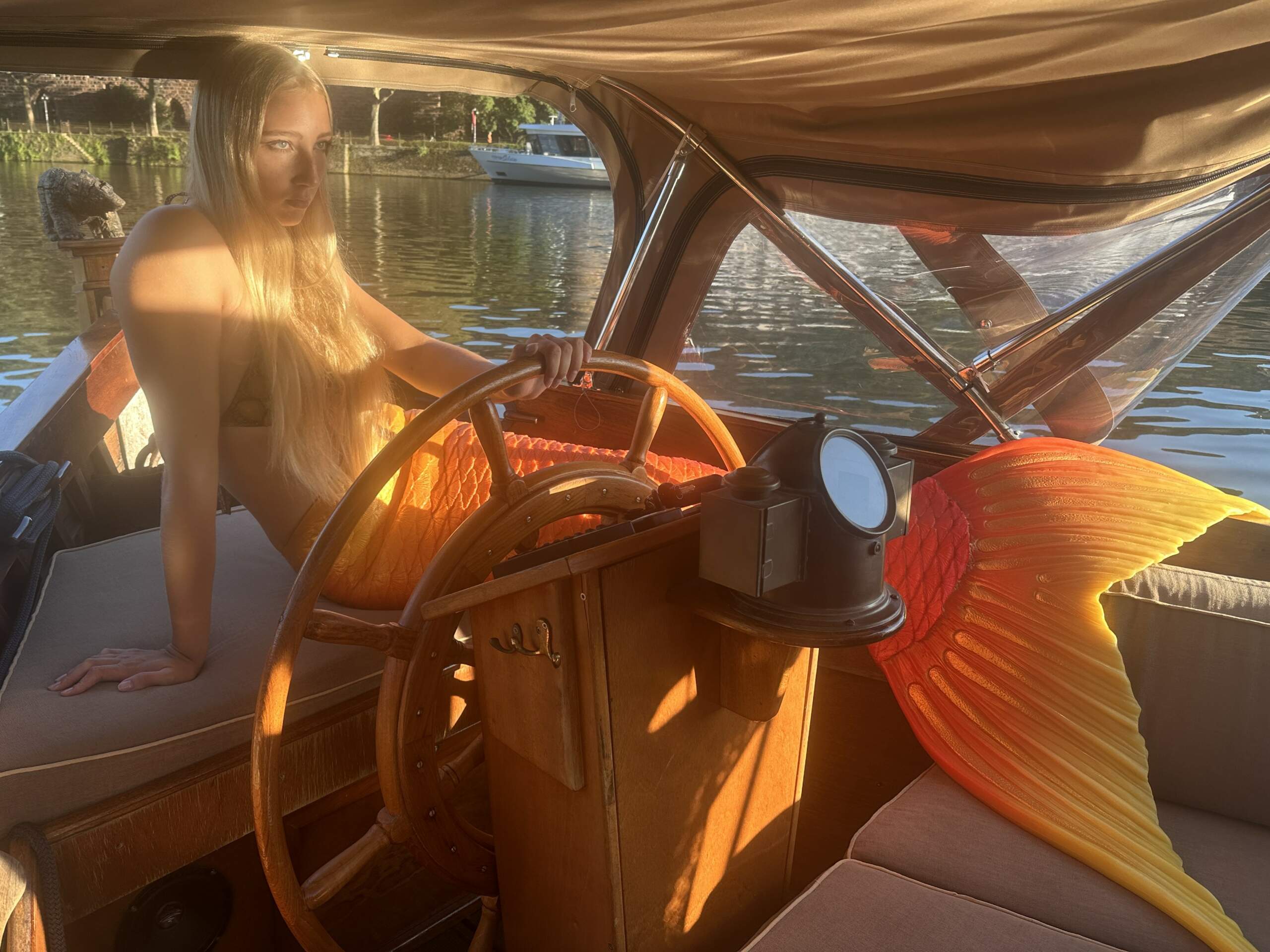 Ein Fotoshooting mit einer Meerjungfrau an Bord des Boots von Riverboat hinter dem Steuerrad