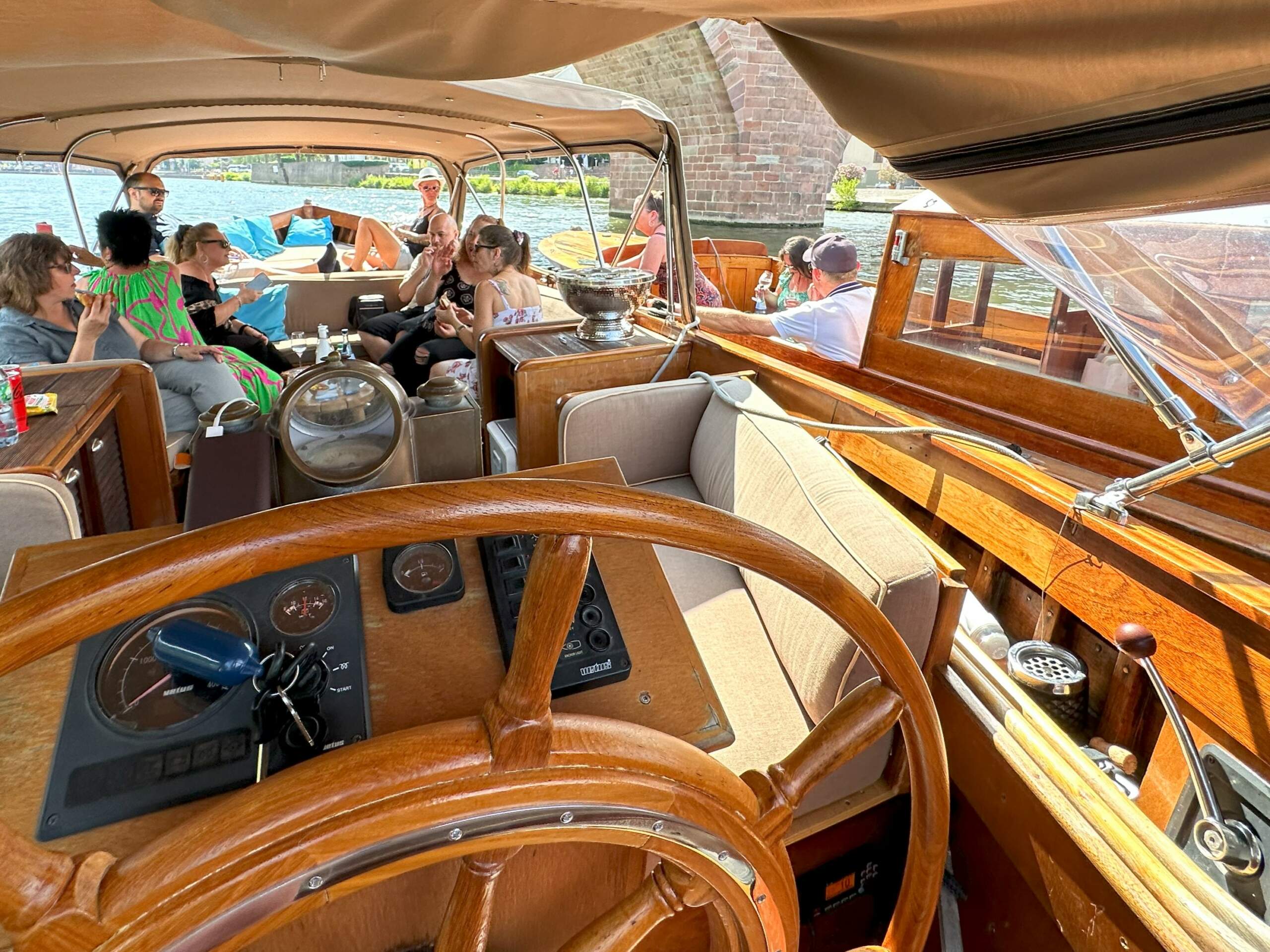 Eine Gruppe Touristen beim Sightseeing mit City Guide und Wein bei Sonnenschein an Bord des Boots von Riverboat