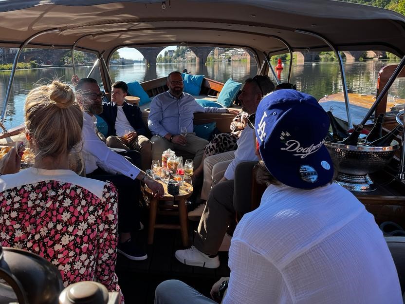 Eine Gruppe Arbeitskollegen sitzen bei einem Teambuilding am Boot von Riverboat, sie trinken Wein und essen Snacks